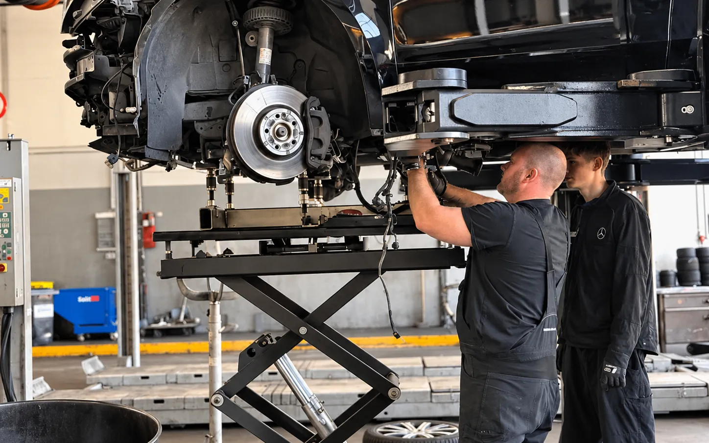 Zwei Mechatroniker reparieren die Vorderachse eines Nutzfahrzeugs in der Werkstatt in Neuss