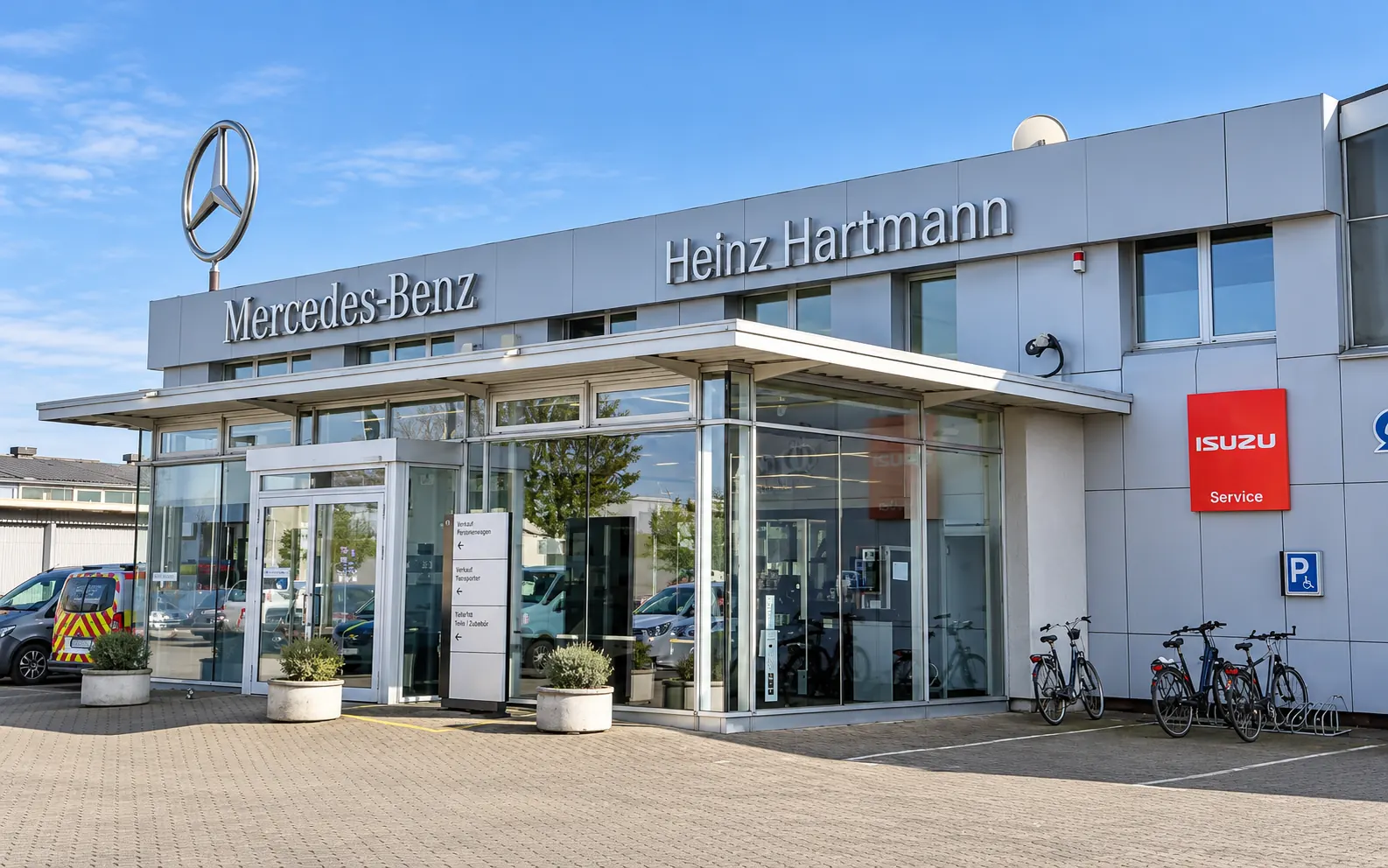 Moderne Servicehalle von Automotive Hartmann in Neuss mit Mercedes-Benz-Stern auf dem Dach und Isuzu-Schild