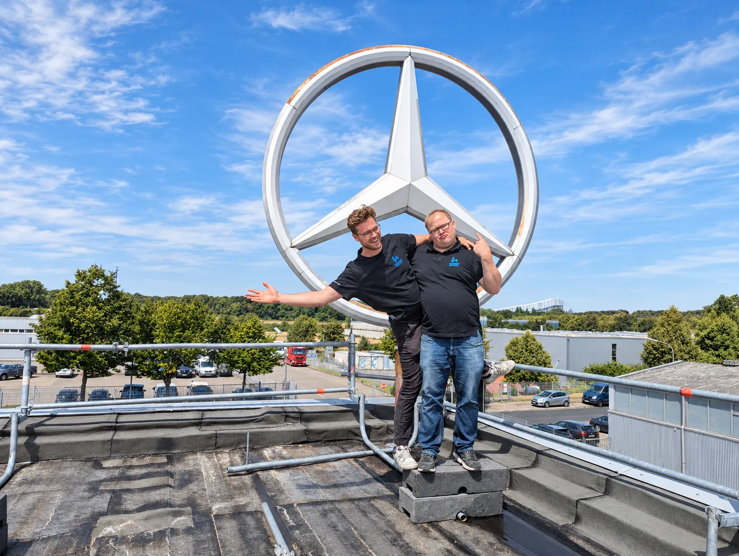 Zwei Mitarbeiter von Automotive Hartmann auf dem Dach vor dem Mercedes-Stern