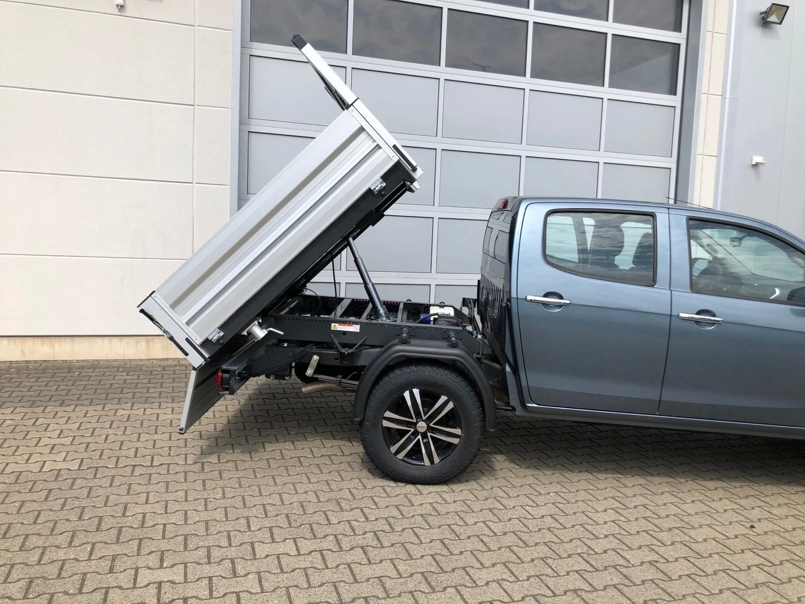 Isuzu D-Max mit Aluminium-Dreiseitenkipper mit Kabinenschutzgitter, Zusatzluftfederung, Bilstein Stoßdämpfer, Hilltip SnowStriker Schneepflug, Hilltip IceStriker Streuer, Quick Hitch Anbausystem, Lichtträger mit LED-Arbeitsscheinwerfern, Hilltip Bedieneinheit mit Joystick