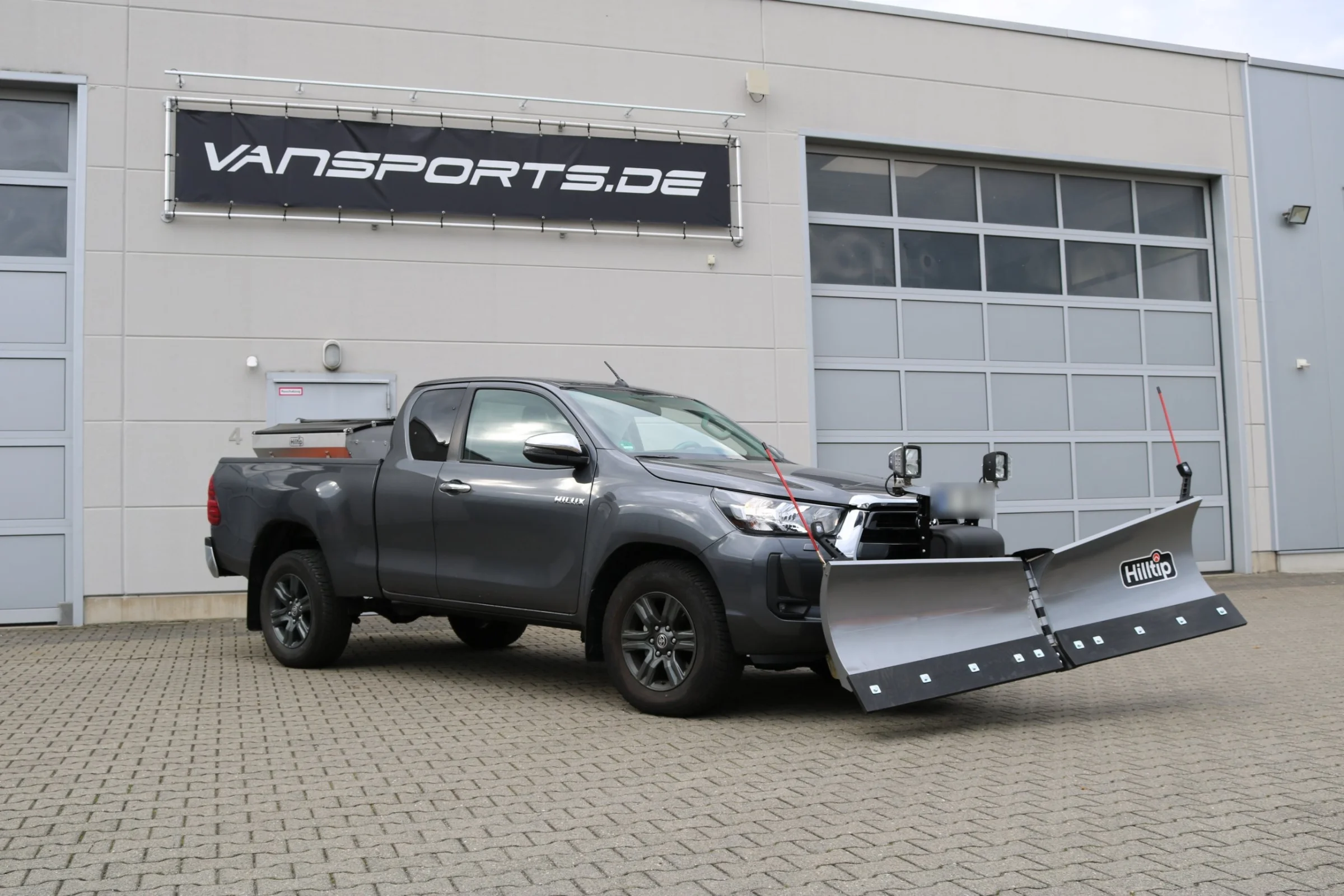 Toyota Hilux mit Hilltip SnowStriker V-Schneepflug, Hilltip IceStriker Streuer (Edelstahl), Quick Hitch Anbausystem, Lichtträger mit LED-Arbeitsscheinwerfern, Schutzabdeckung für die Anbauplatte