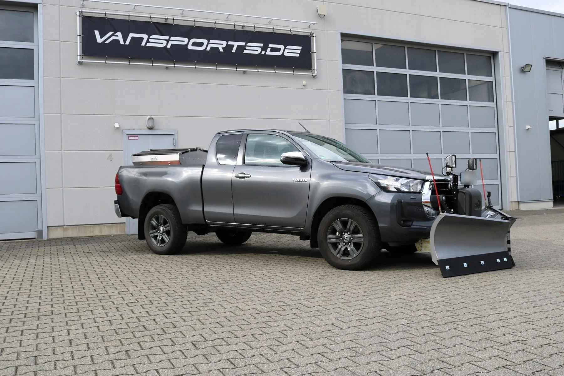 Toyota Hilux mit Hilltip SnowStriker V-Schneepflug, Hilltip IceStriker Streuer (Edelstahl), Quick Hitch Anbausystem, Lichtträger mit LED-Arbeitsscheinwerfern, Schutzabdeckung für die Anbauplatte